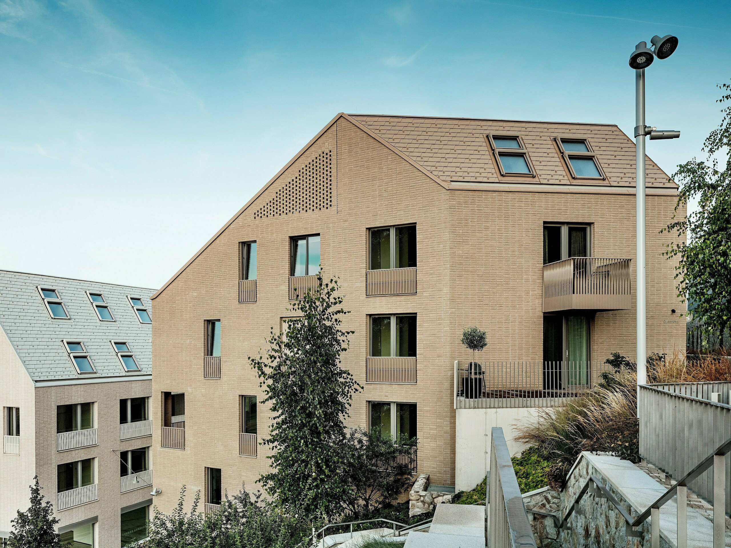 Moderne Wohnbauten im Stadtquartier Vydrica in Bratislava mit klarer, reduzierter Formensprache und harmonischer Einbindung in die Topografie: Die steilen Satteldächer mit präzise verlegten PREFA Aluminium Dachschindeln in P.10 Sandbraun und Prefaweiß setzen mit ihren strukturierten Oberflächen und integrierten Dachfenstern starke visuelle Akzente. Die einheitliche Gestaltung von Dach und Fassade schafft ruhige, hochwertige Flächen. PREFA Aluminium überzeugt durch Langlebigkeit, leichte Verarbeitung, hohe Witterungsbeständigkeit und ermöglicht anspruchsvolle, nachhaltige Dachlösungen.