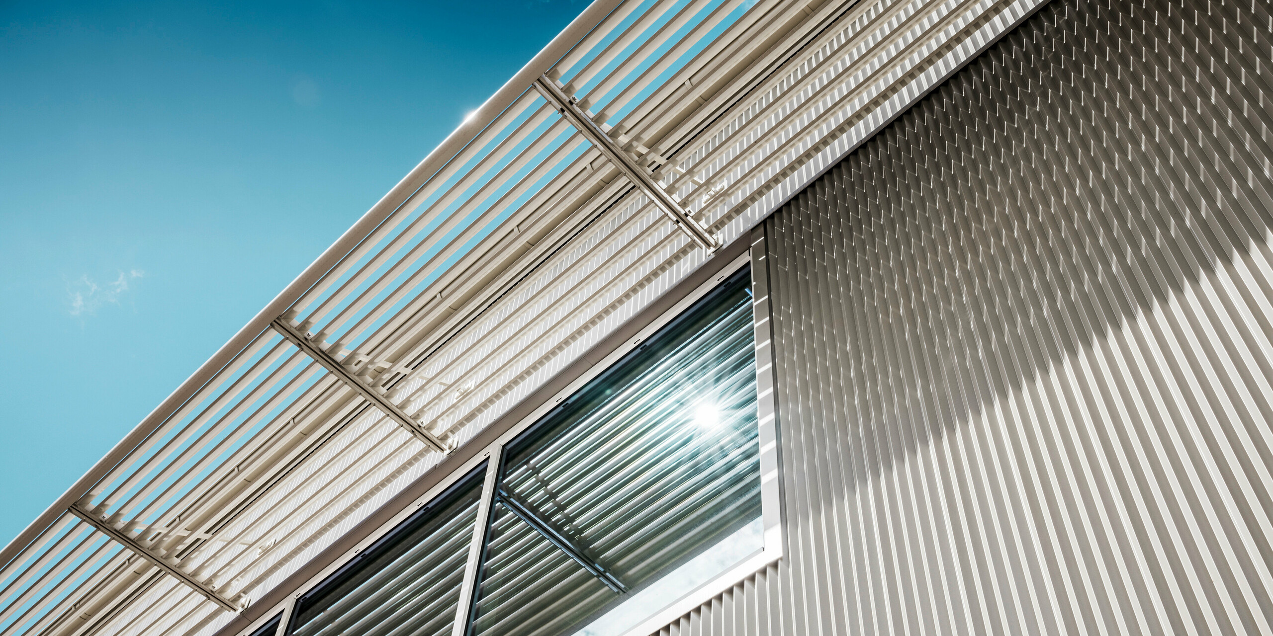 Nahaufnahme der Fassade der Park Arena in Värnamo, Schweden. Das PREFA Zackenprofil in Bronze macht die Sportstätte zu einem architektonischen Blickfang. Die präzise integrierten Fenster und der darüber liegende Sonnenschutz unterstreichen das moderne und elegante Design des Sportzentrums. Die gezackten Profile aus stranggepresstem Aluminium erzeugen markante Licht- und Schatteneffekte.