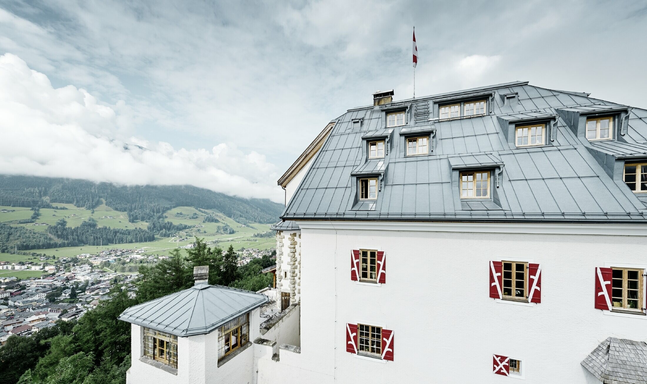 Mittersill Castle surrounded by trees and mountains with a recently renovated Prefalz roof in stone grey