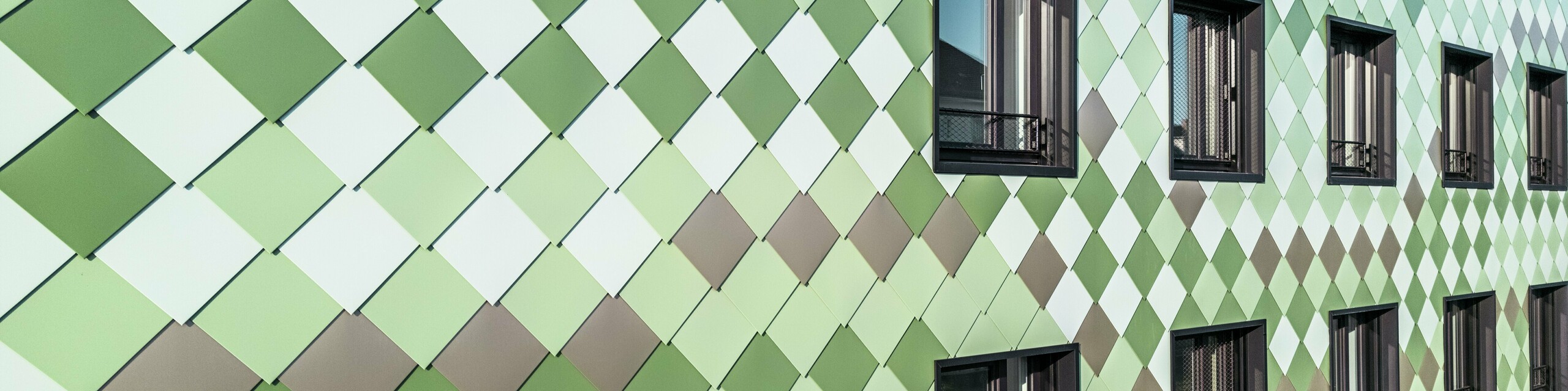 Modern PREFA façade cladding with PREFA rhomboid tiles in specially developed colours: olive green, grey-green, reseda green, opal green, light ivory, pearl white and light bronze. The ‘Pick-Nick’ residential and commercial building in Dresden impresses with its unique look, weather resistance, durability and maintenance-free quality. The stylish design and variety of colours set architectural accents and offer lasting protection.