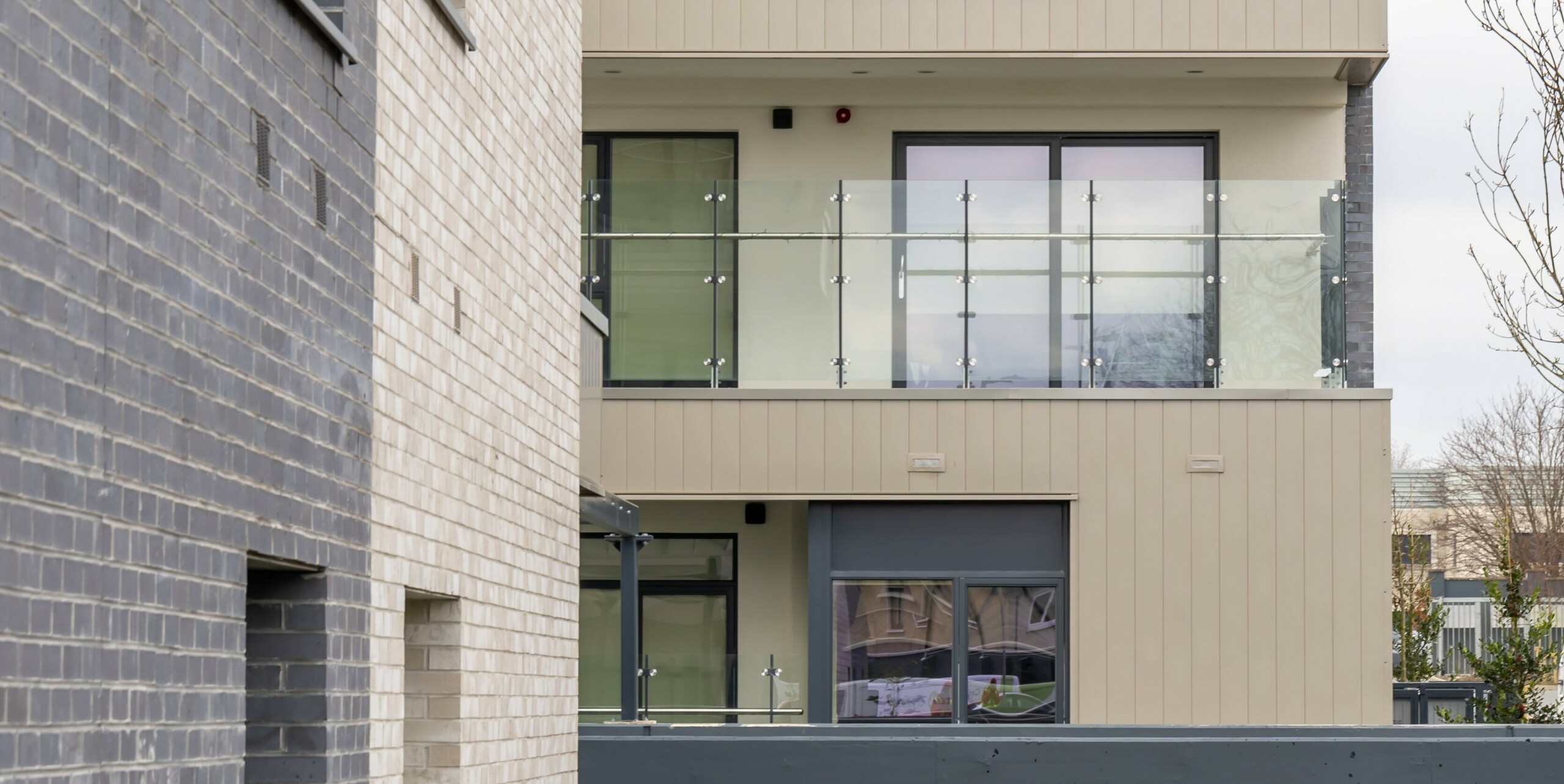 Detailed view of the façade of the Palmers Gate residential complex in Palmerstown, Dublin, Ireland. The picture shows the combination of bronze-coloured PREFA aluminium products and brick elements. The balconies are fitted with glass balustrades and offer modern living quality. The outer cladding consists of approx. 1,700 m² of PREFA sidings and approx. 1,200 m² of the PREFALZ façade system. The picture emphasises the architectural details and the high-quality choice of materials, which contribute to the aesthetic and functional design of the buildings.