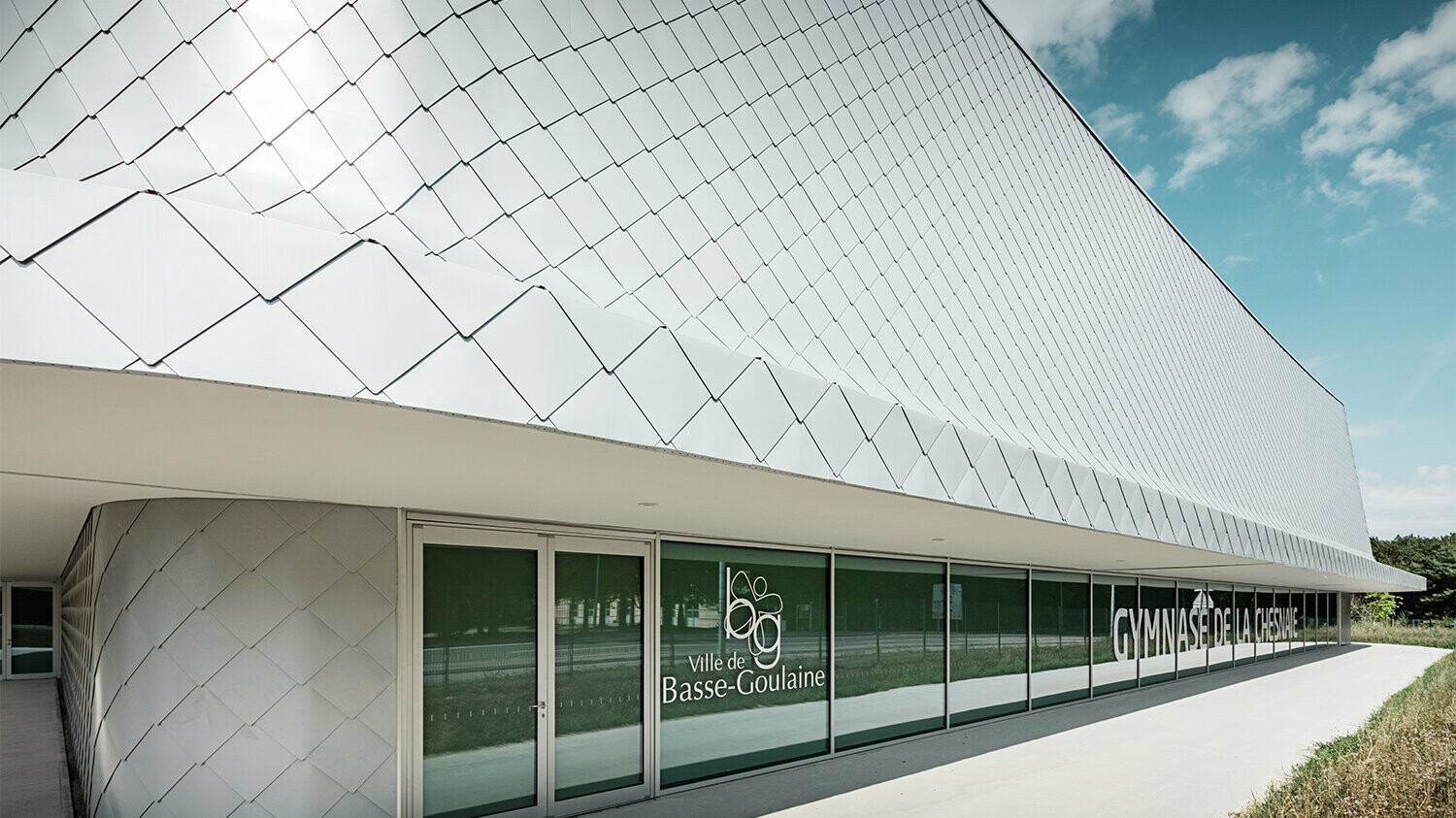 Lateral close-up of the building, the transition between roof and façade is seamless.