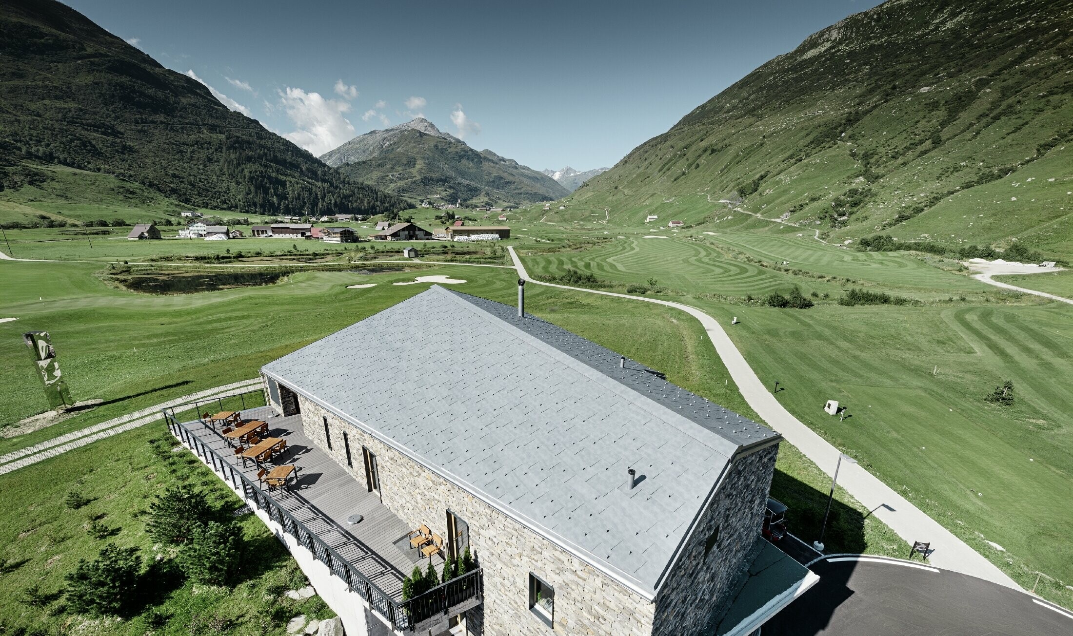 Modern club house at Andermatt golf course (Switzerland) with a stone façade and aluminium PREFA FX.12 roof panels in stone grey