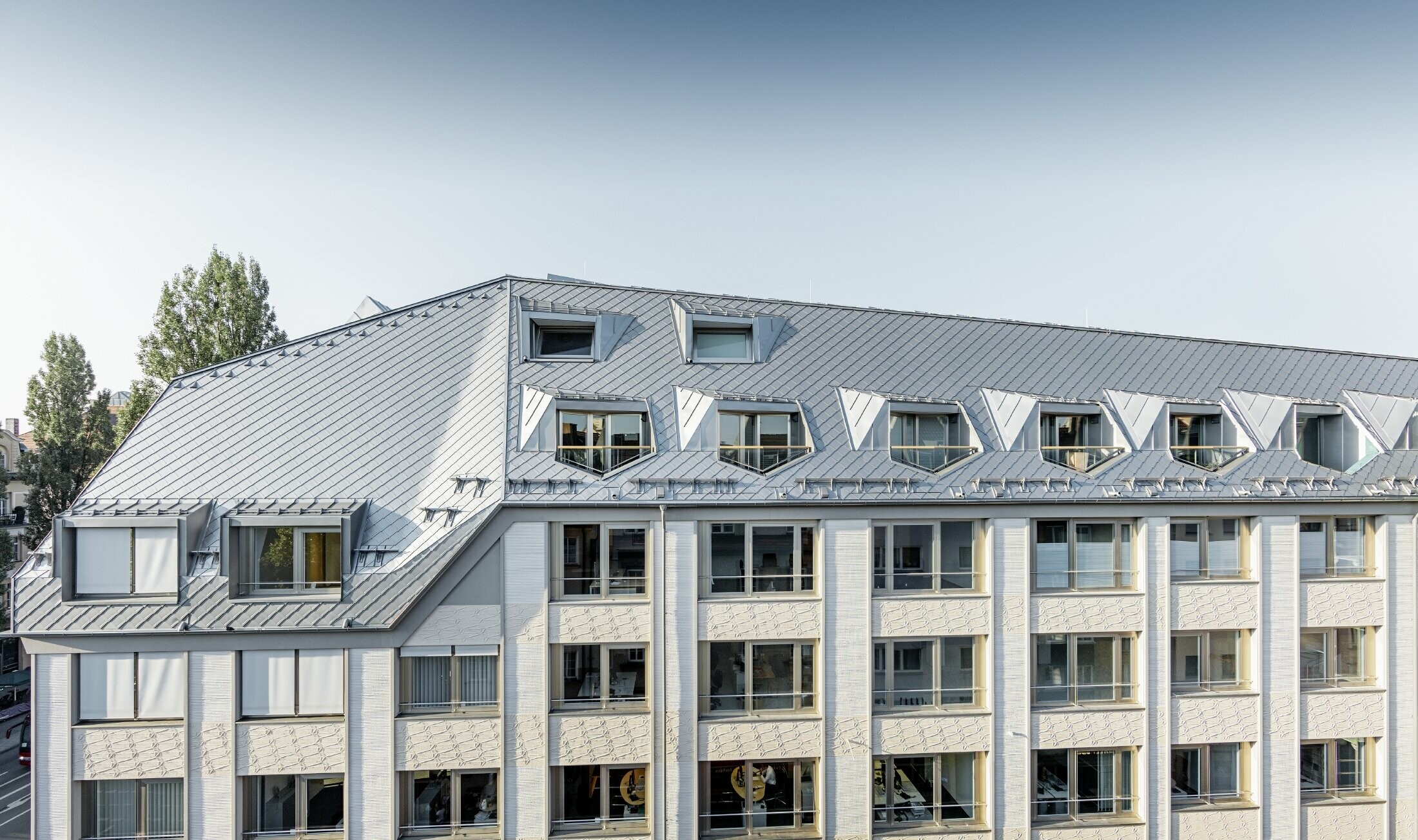 Renovated mansard apartments with large, open galleries in a residential and commercial building in Leopoldstraße/corner of Hohenzollernstraße in Munich (Germany), with a roof covering made of PREFA rhomboid roof tiles