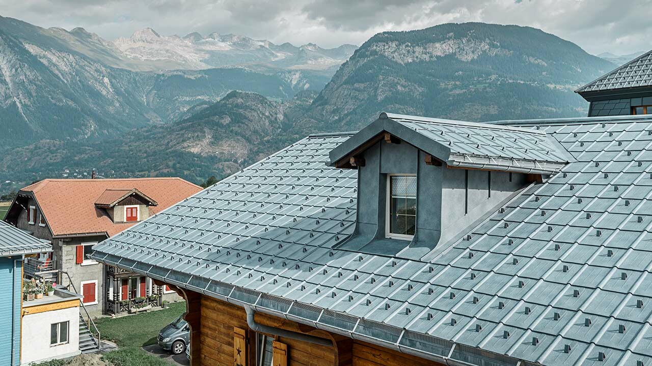 Gabled roof with dormers. A PREFA sheet metal roof is installed on the roof area with the roof tiles in stone grey. The dormer is clad in a PREFA angular standing seam in stone grey.