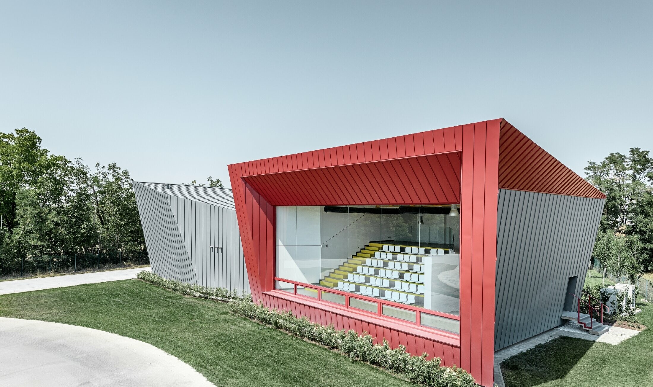 Dieci’s modern training centre in Montecchio Emilia (Italy), with a tribune displaying an aluminium façade in light grey Prefalz and crimson Falzonal