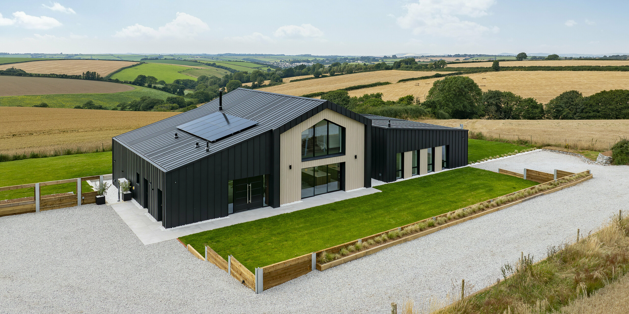 The front of the modern detached house ‘The Hide’ shows the harmonious combination of contemporary design and high-quality architecture. The PREFALZ standing seam roofing in the colour 0P.10 anthracite covers the roof and façade and, together with the generous window areas and wooden accents, forms a visually appealing unit.