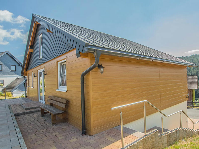 Residential building with a non-bearing, rear-ventilated façade by PREFA with light wood-effect sidings and rhomboid façade tiles.