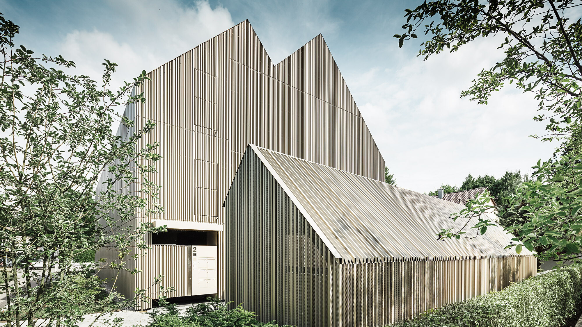 Side view of the residential building and its matching bicycle shed.