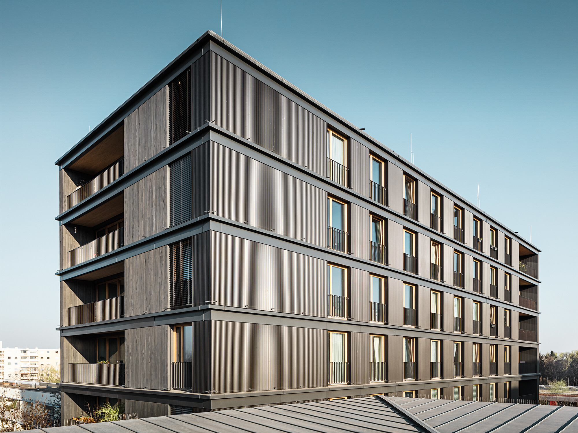 PREFA ripple profile in black grey on a German residential and commercial building The residential and commercial building from the side: it is difficult to tell the difference between the PREFA ripple profile and the timber façade.