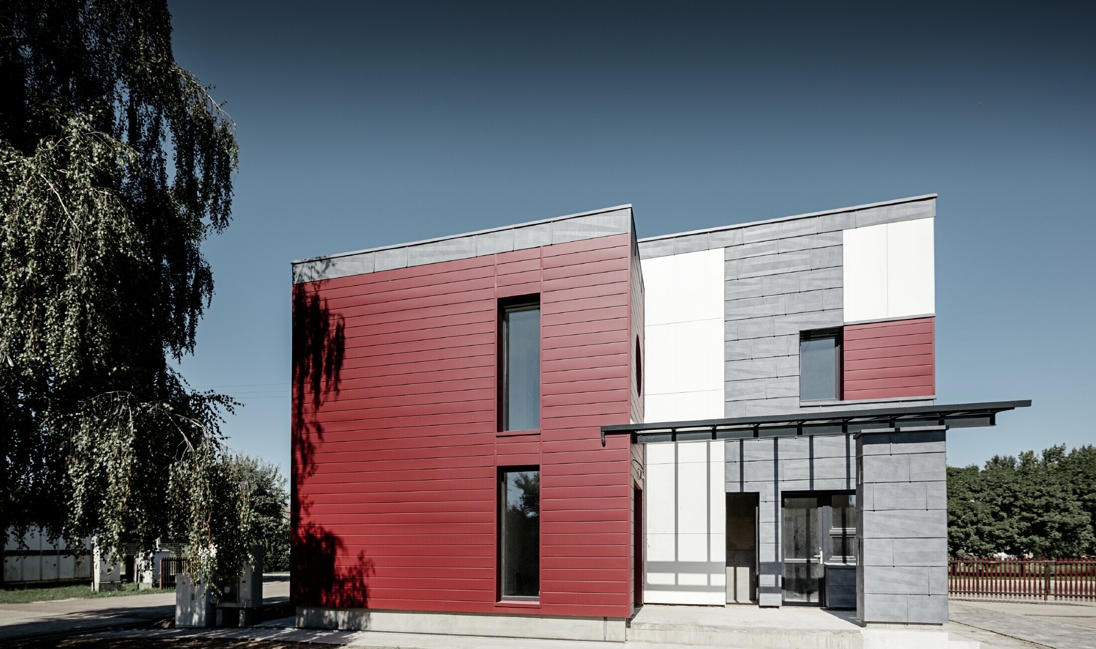 Modern office building with a divided façade in red, stone grey and white, and sidings, FX.12 façade panels and aluminium composite panels made by PREFA Aluminiumprodukte GmbH