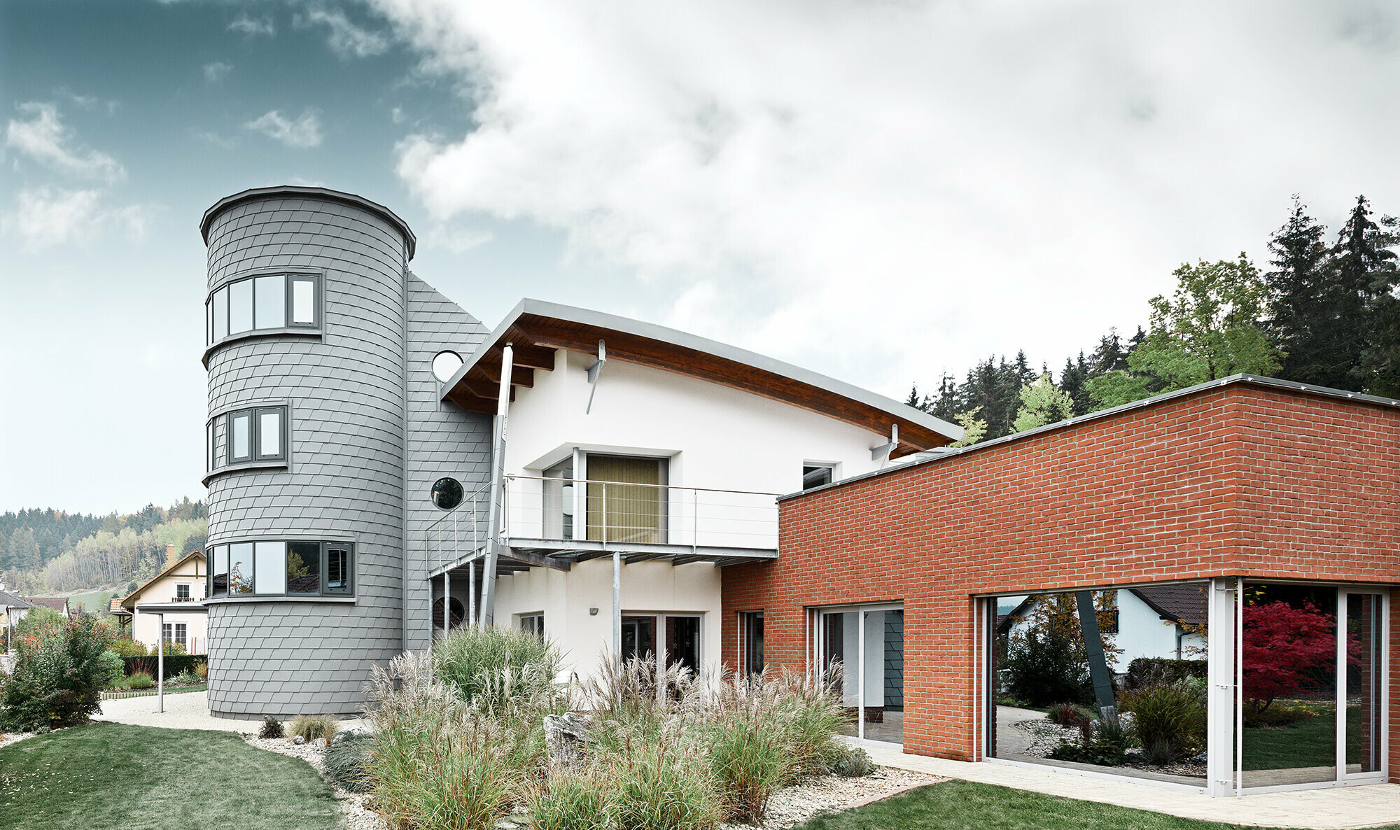 Detached house with tower extension, the round tower is clad with PREFA façade shingles in patina grey 