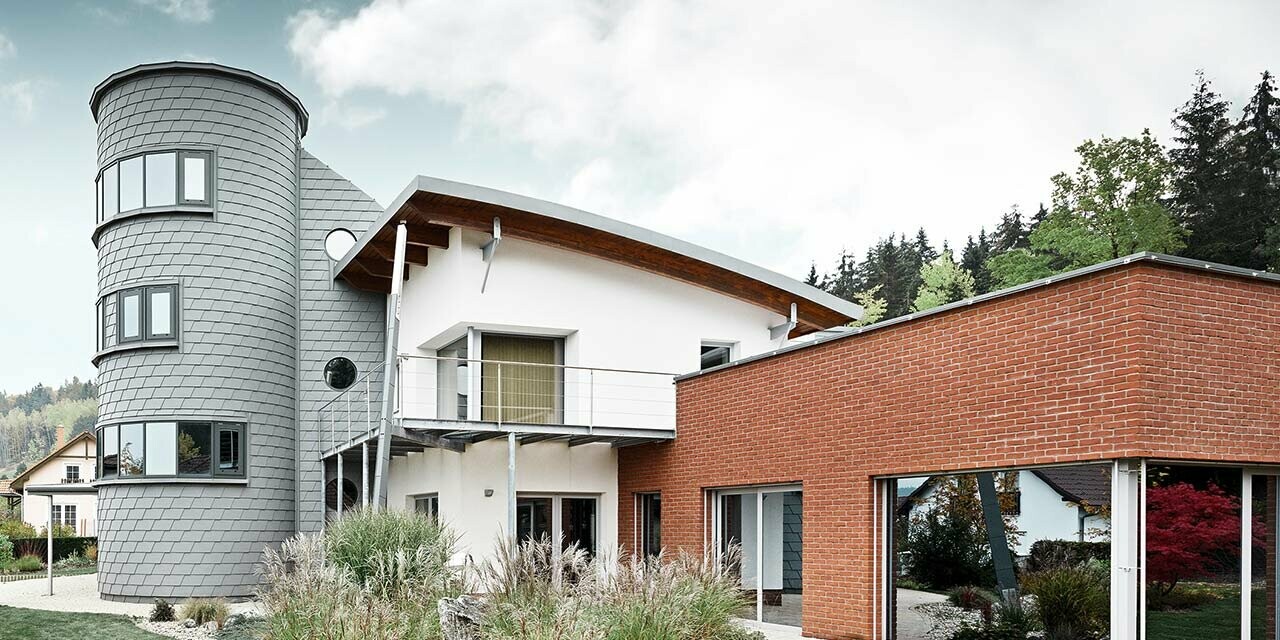 Detached house with tower extension, the round tower is clad with PREFA façade shingles in patina grey 