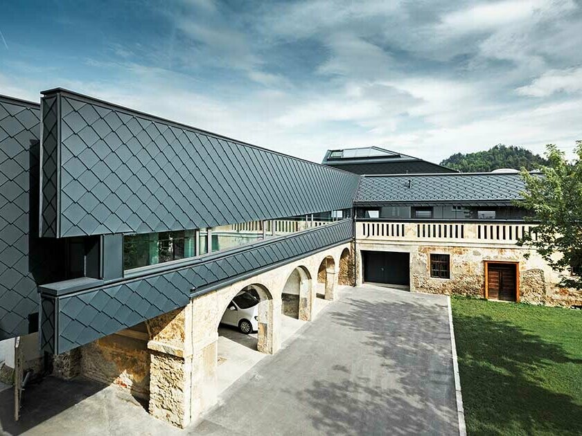 The BH Völkermarkt building is a mixture of old and new building materials, the ground floor is still made from old stone wall, while the upper floor is clad with modern PREFA roof tiles 29 × 29 in anthracite.