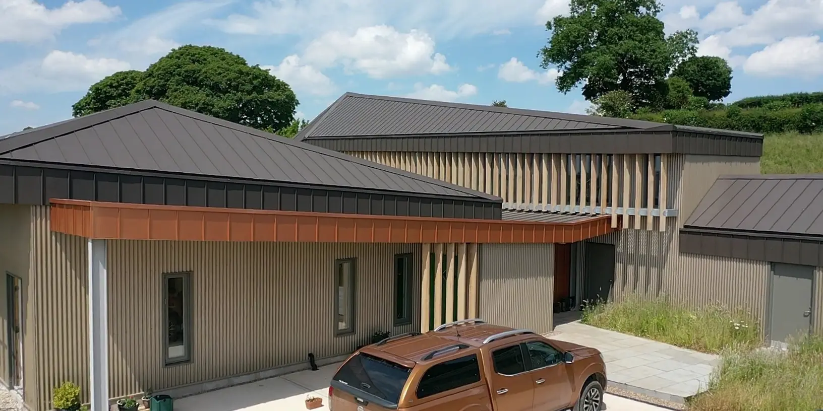 Entrance area of a longhouse in Derbyshire with parking space and a car