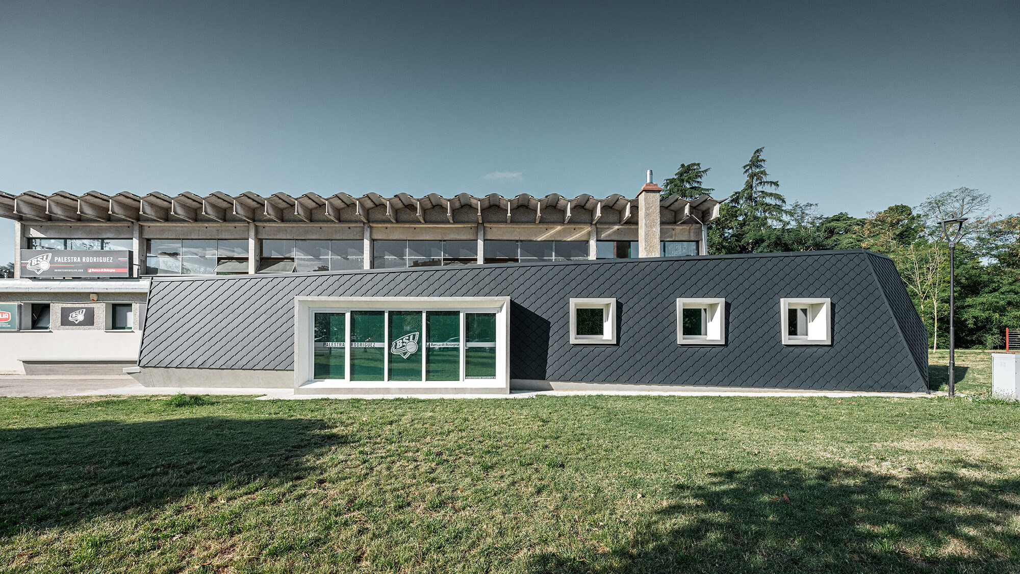 A side view of the gymnasium extension; the colour of the aluminium façade appears to change in the sunlight. 