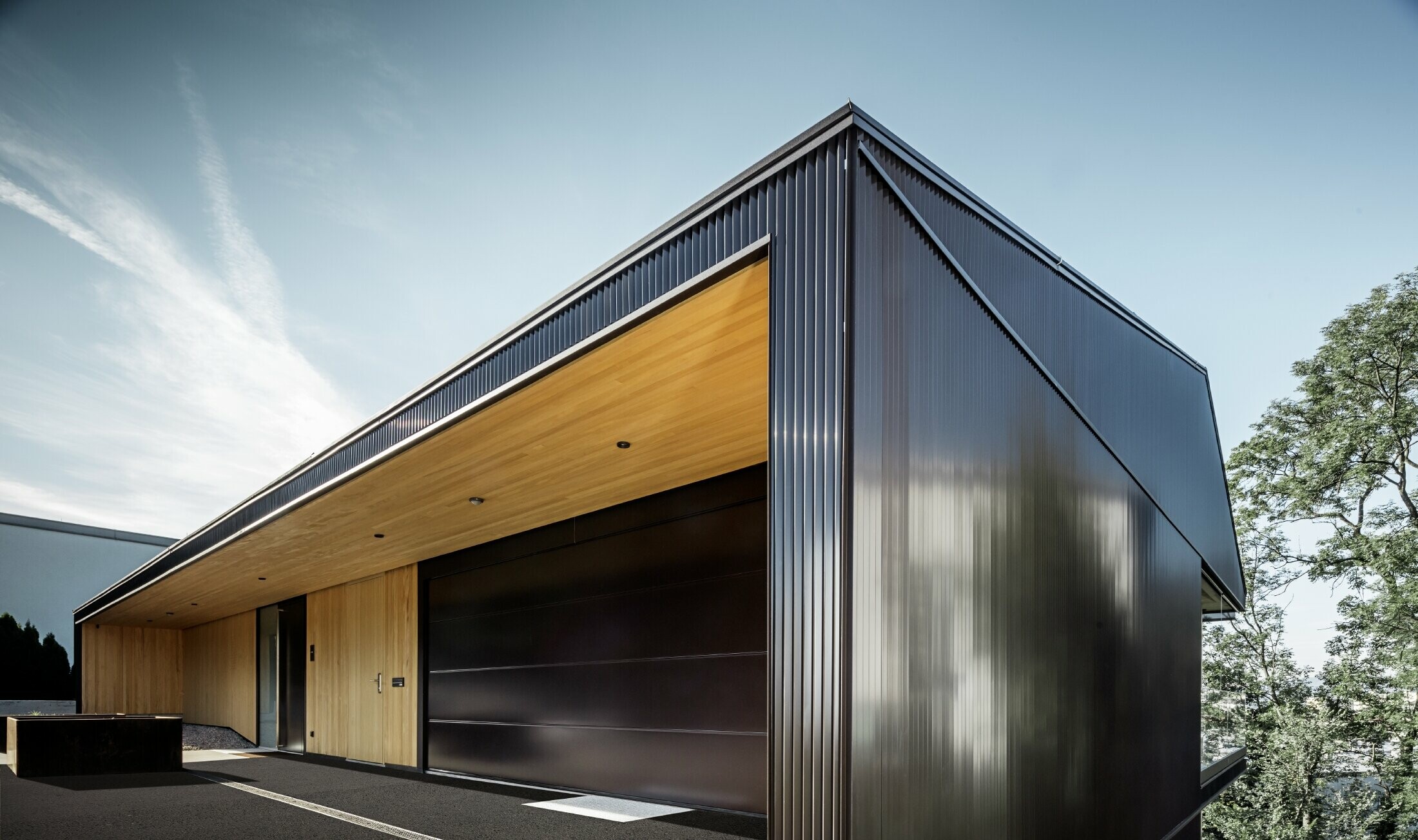 Garage entrance to a detached house; the façade is clad with the PREFA zig-zag profile in dark brown. 