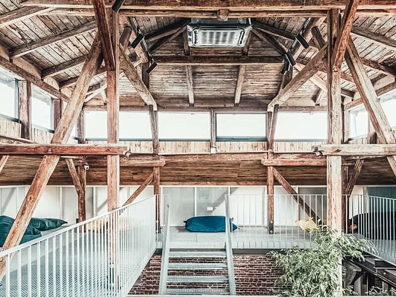 A photo of the attic of the building, with the wood structure roughly preserved. A staircase leads up to it.