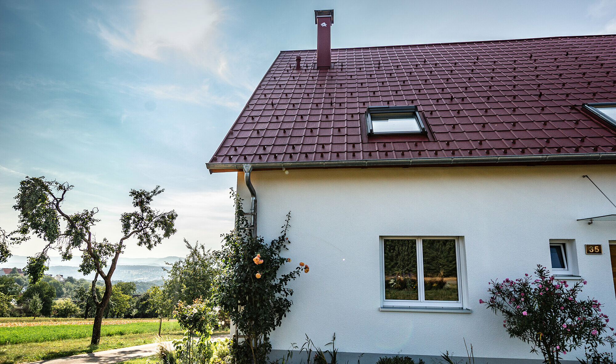 Rural cottage with refurbished roof using the PREFA roof tile in oxide red, roof window and chimney surround.