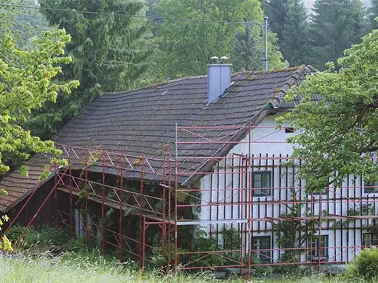 Old roof on a rural cottage (with scaffolding) just before the roof was renovated with PREFA shingles
