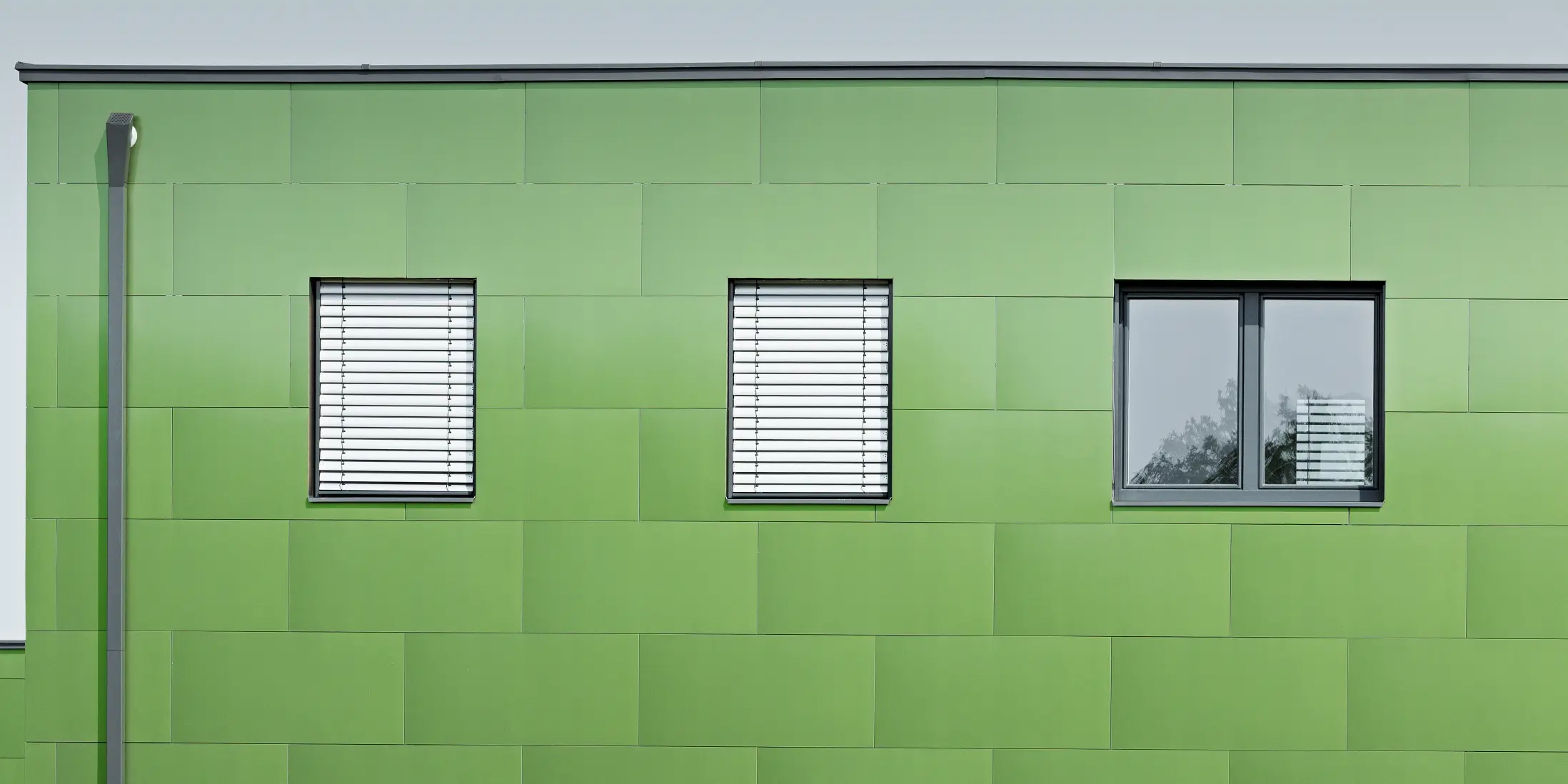 Frontal view of the PREFA aluminium composite panel with chameleon look and changing colours. On the far left, you can see the PREFA square downpipe
