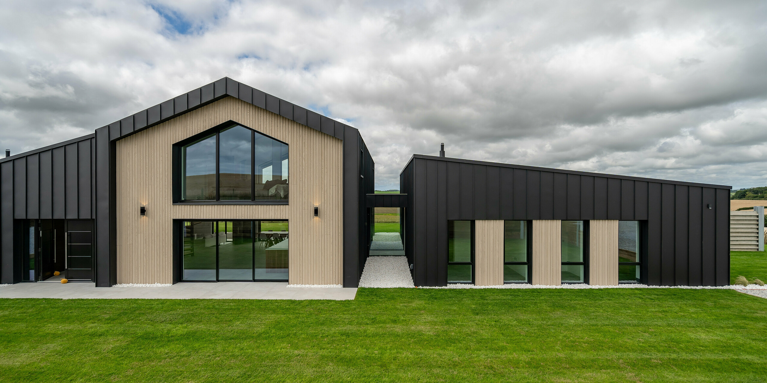 Front view of the modern single-family house ‘The Hide’ in Cornwall with PREFALZ roof and facade cladding in P.10 anthracite. Clear lines, light wooden elements and large window areas complement the dark standing seam cladding from PREFA. The robust aluminium shell gives the building a timeless elegance with long-lasting weather protection.