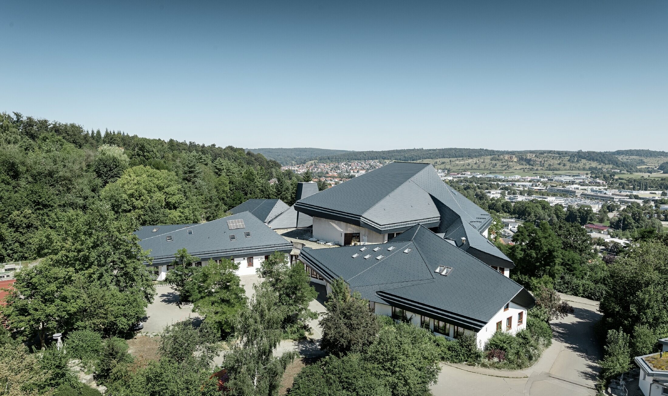 Waldorf school in Heidenheim (Germany) with a newly renovated roof. The large roof surface with its many angles and roof pitches was covered with PREFA shingle in anthracite