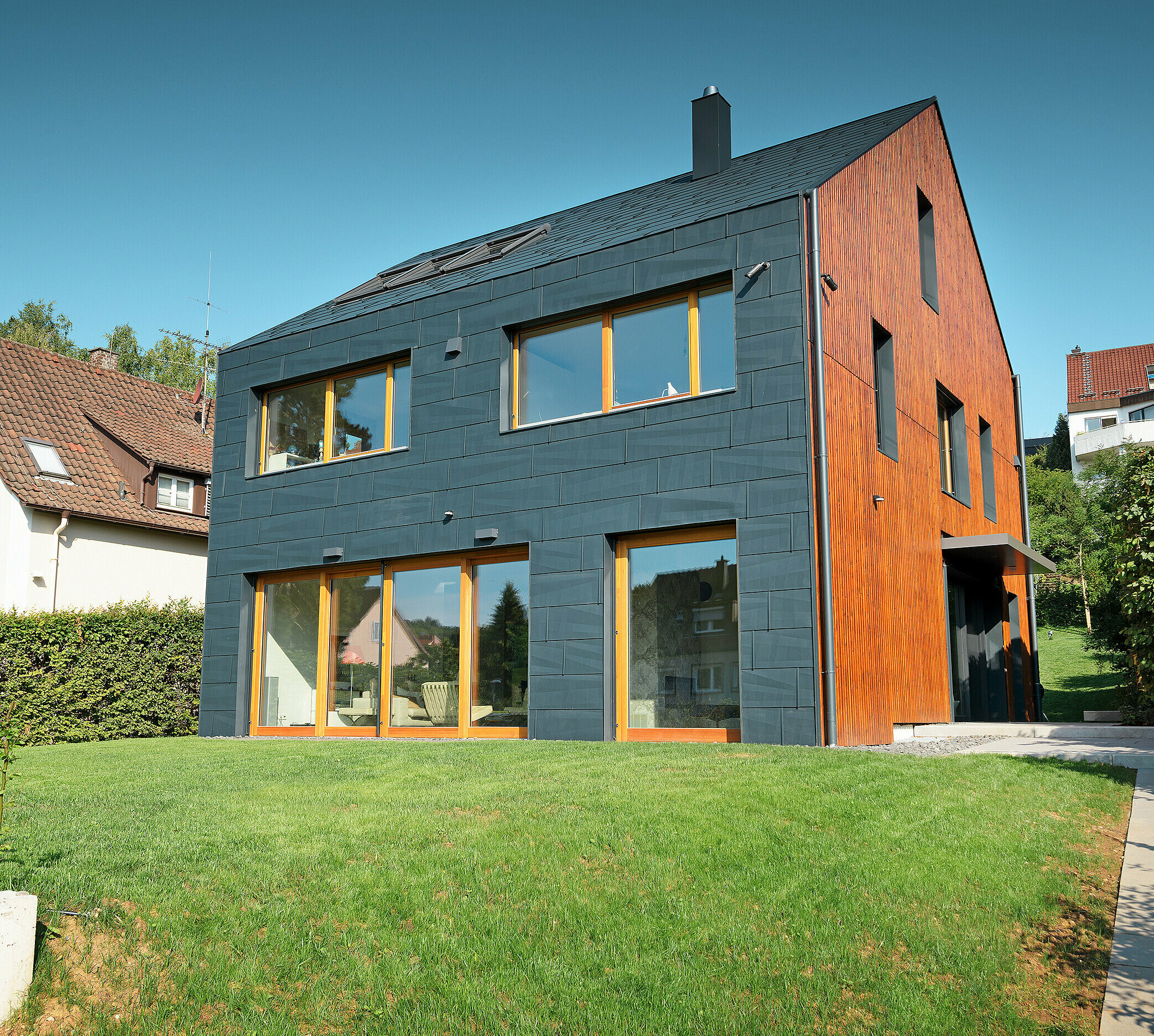 The PREFA FX.12 façade in P.10 anthracite extends from the façade over the gable roof without any overhang.