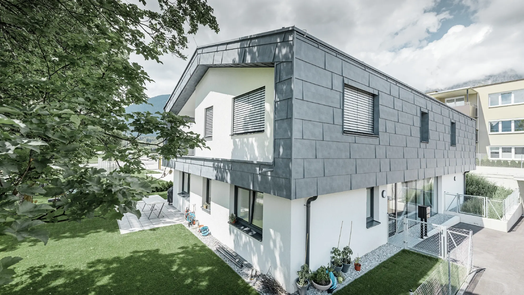 Addition of a modern storey on a residential building with flat gabled roof and no soffit; the PREFA FX.12 façade panel in stone grey was used for the façade cladding.