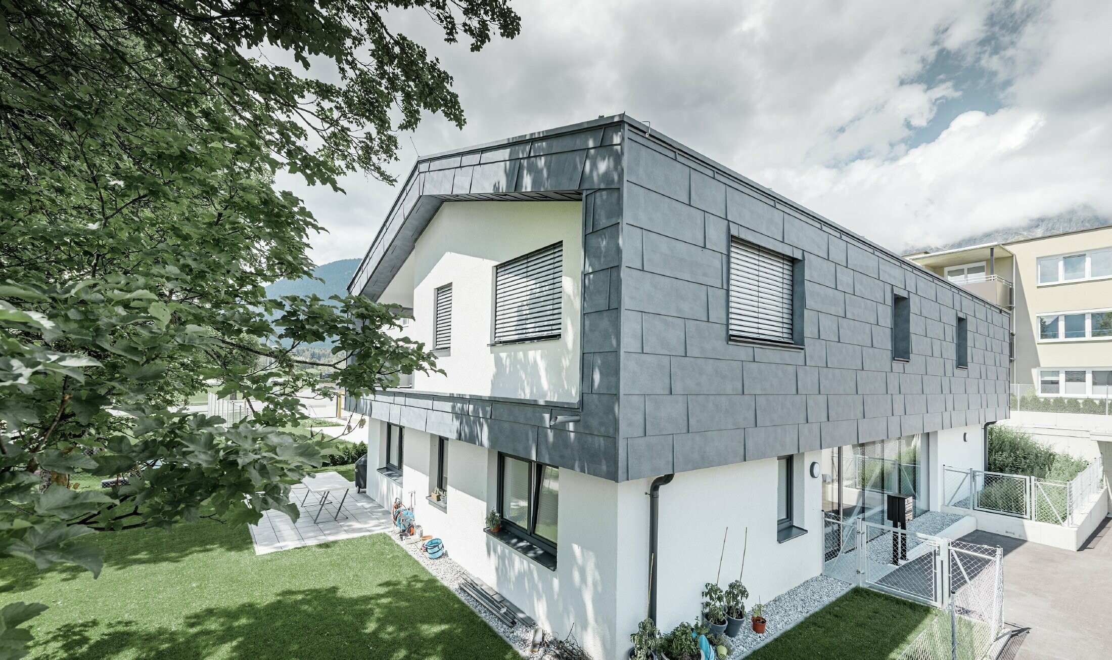 Addition of a modern storey on a residential building with flat gabled roof and no soffit; the PREFA FX.12 façade panel in stone grey was used for the façade cladding.