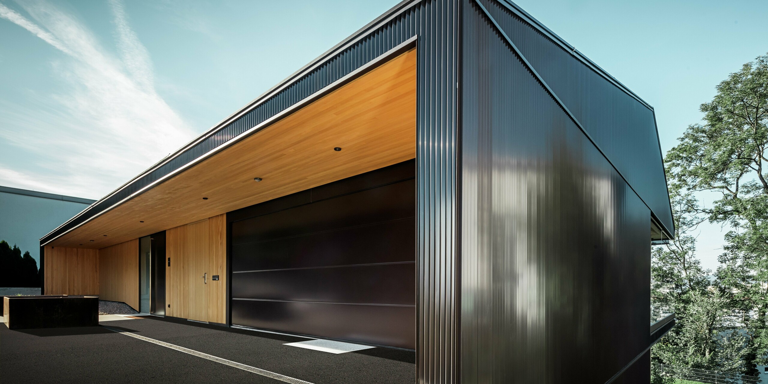 Garage entrance to a detached house; the façade is clad with the PREFA zig-zag profile in dark brown.