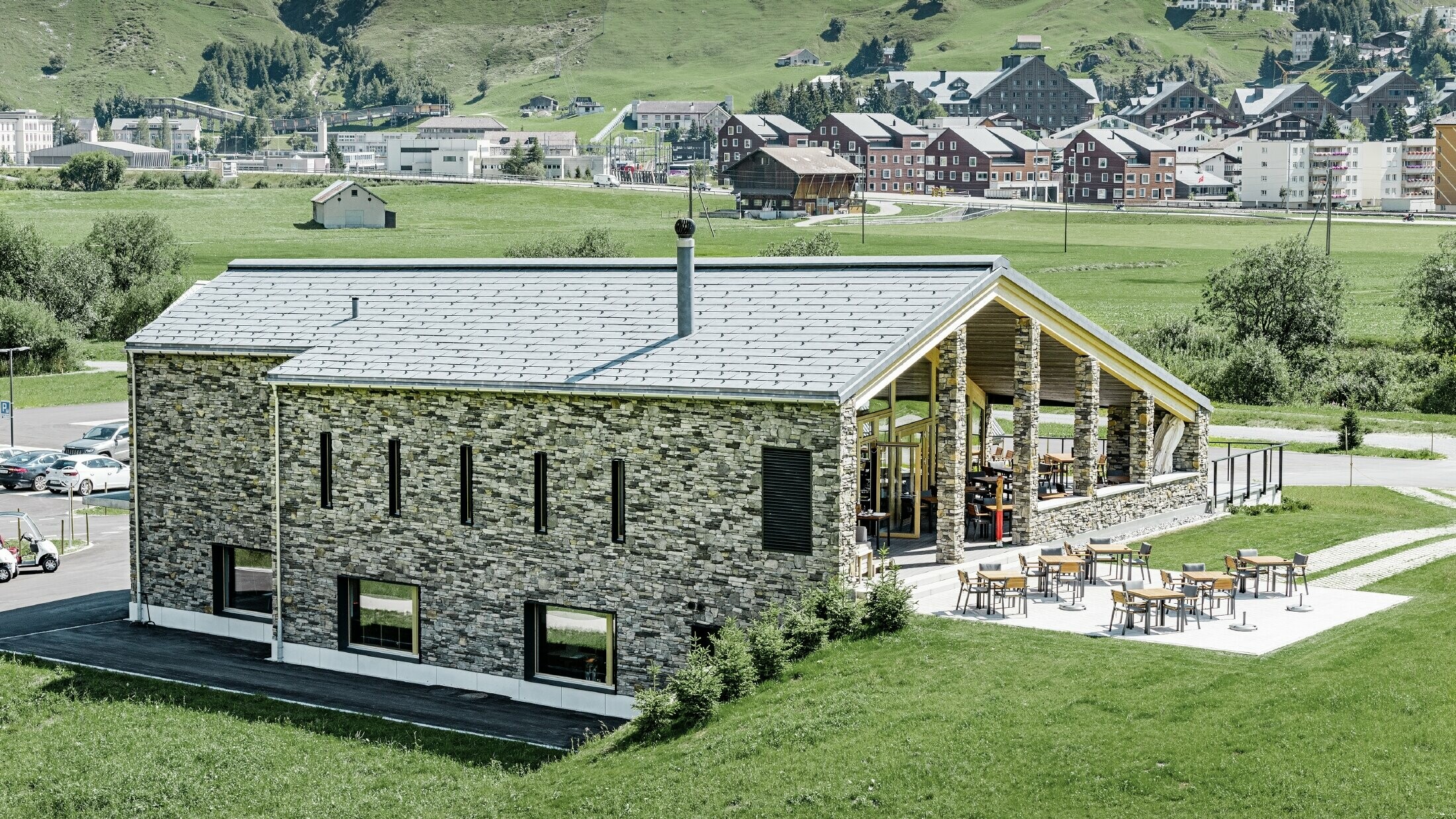 Modern club house at Andermatt golf course (Switzerland) with a stone façade and aluminium PREFA FX.12 roof panels in stone grey