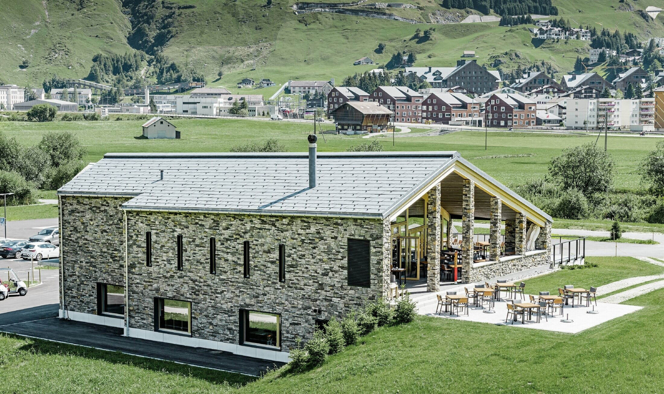 Modern club house at Andermatt golf course (Switzerland) with a stone façade and aluminium PREFA FX.12 roof panels in stone grey