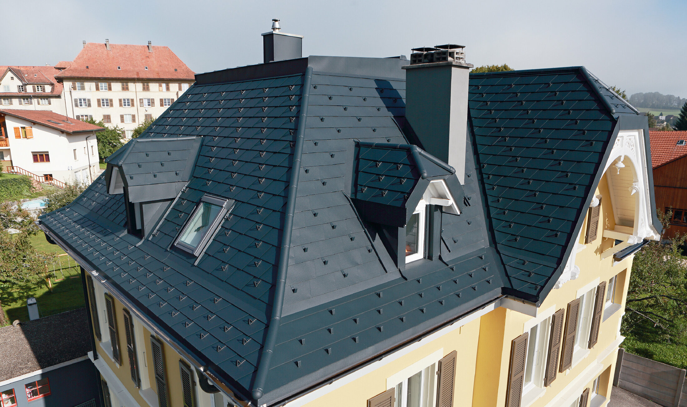 Villa in Switzerland, the roof has many valleys and small dormers, the roof is covered with an aluminium shingle from PREFA in P.10 anthracite.