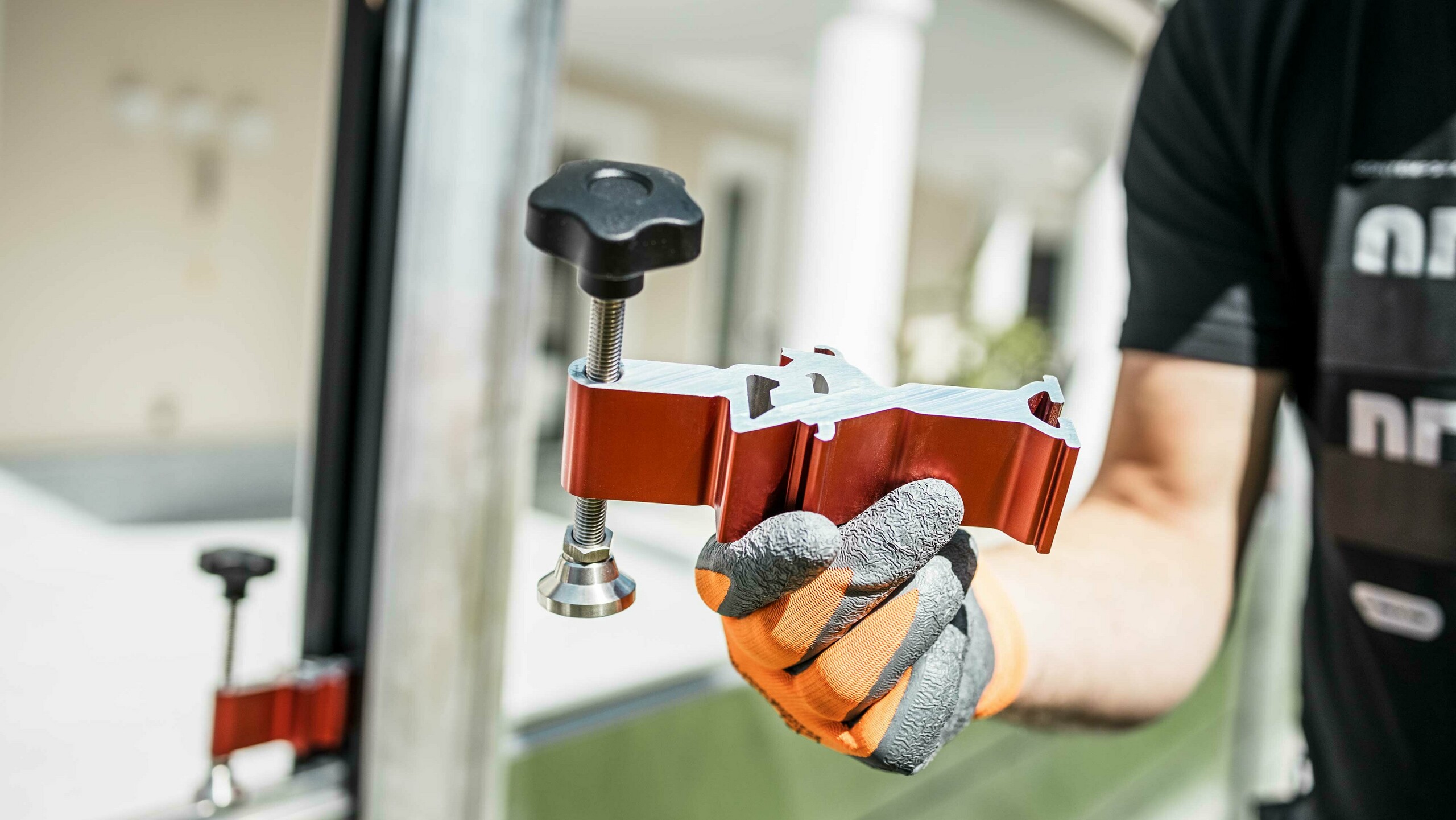 Close-up of the red compression clamping for fastening the barrier panels of the PREFA flood protection system.