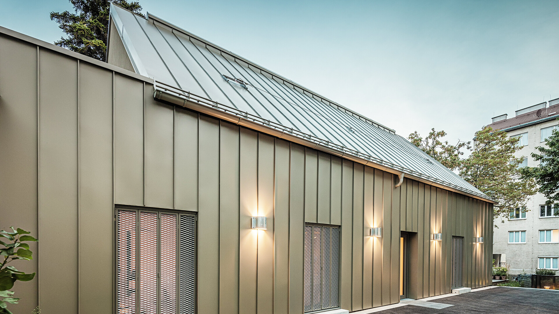 The picture shows a close-up of the Atelier Comploj with a façade and roof made of PREFALZ in the colour P.10 Prefa bronze.
