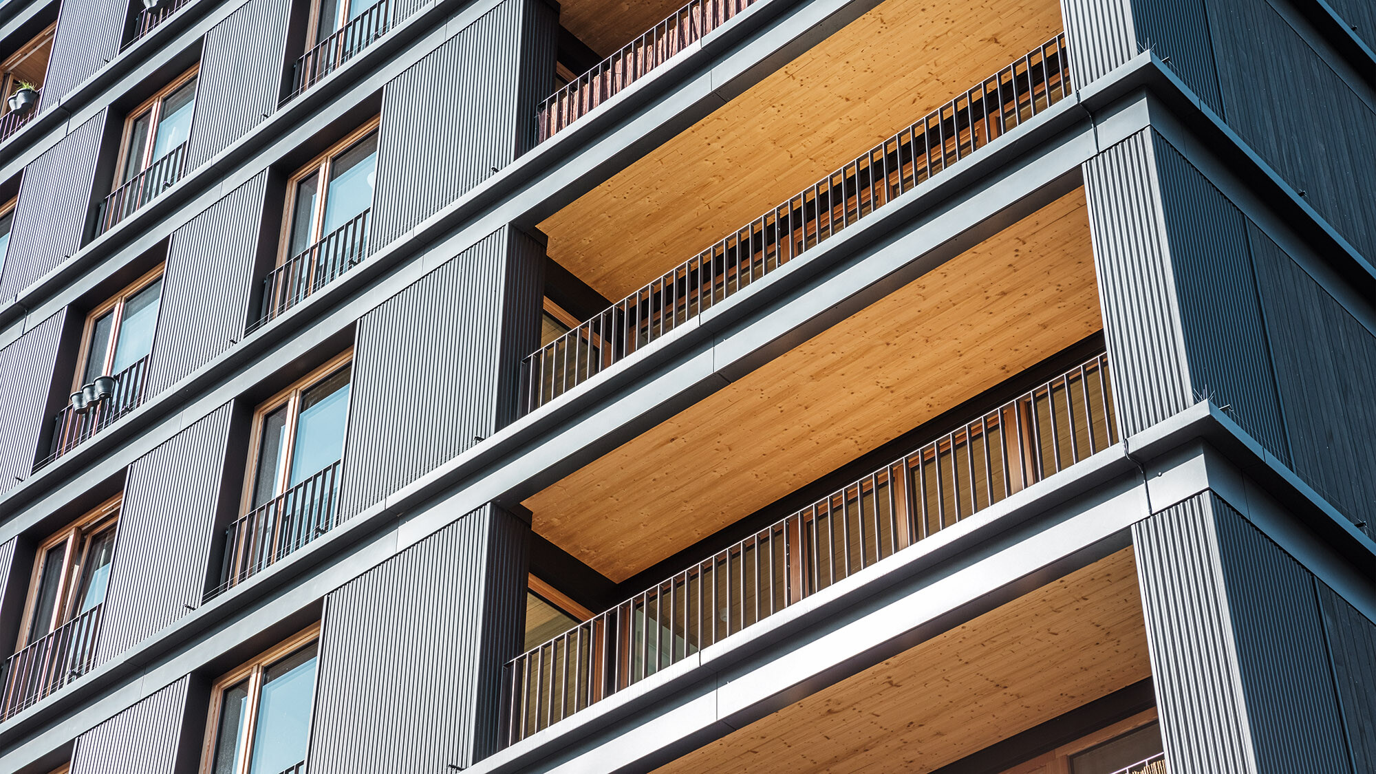 The multifunctional building from a worm's eye view from the side: the ripple profile, balconies and timber-clad balcony ceilings are in view.