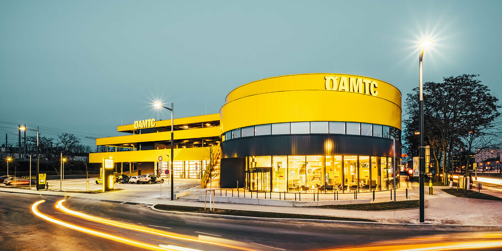 The ÖAMTC Center in Vienna by night. The building is covered in PREFA Sidings in the colour rapeseed yellow.