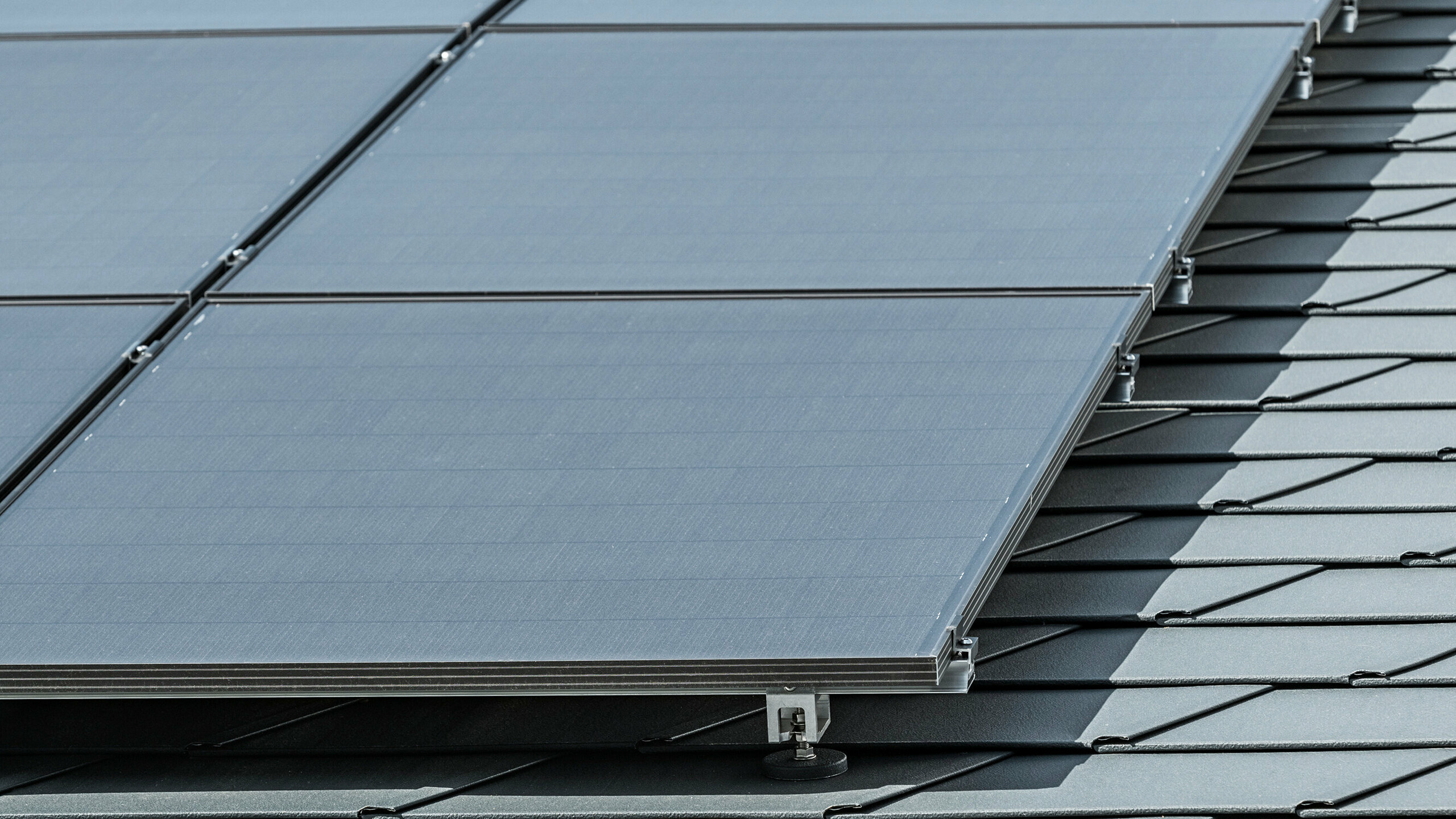 Close-up of a photovoltaic system mounted on PREFA roof shingles DS.19 in P.10 anthracite with PREFA Solar bracket Vario