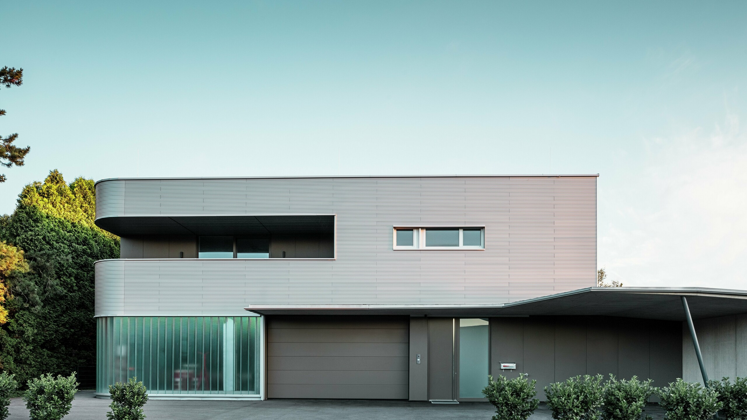 Modern residential building with plain aluminium façade made from PREFA ripple profile with garage in daylight.
