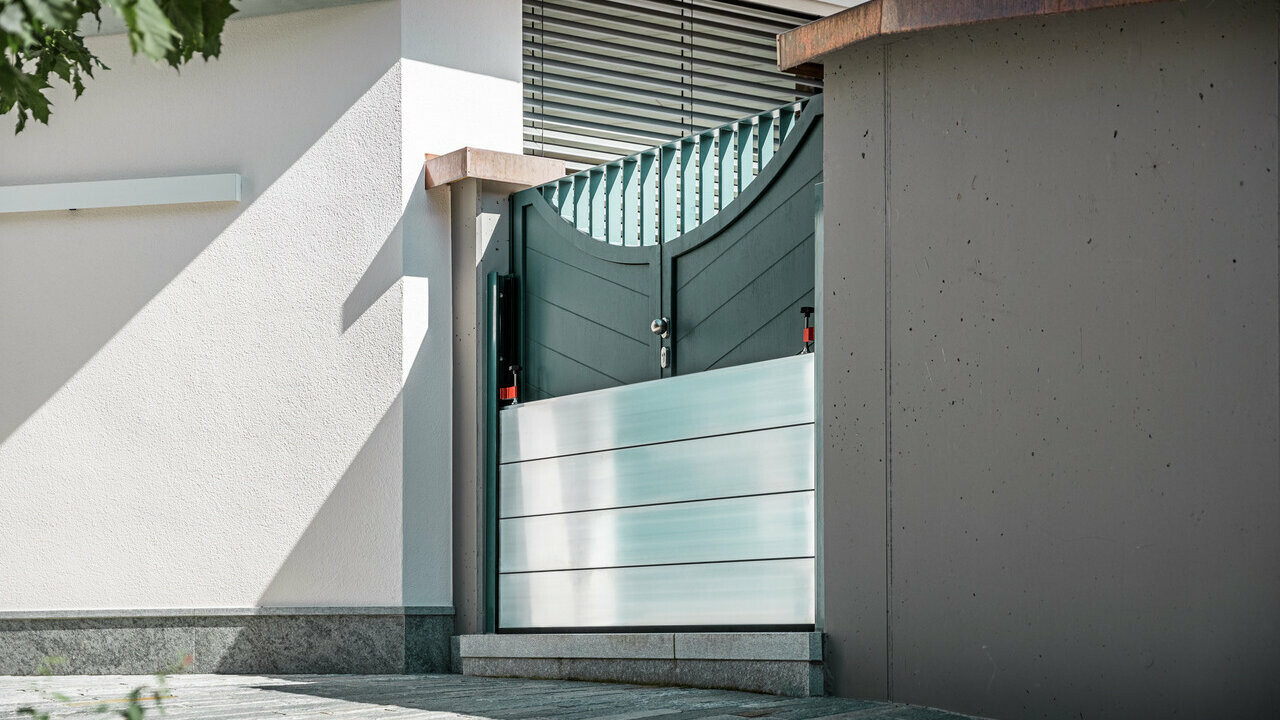 The picture shows a green entrance gate. PREFA's mobile flood protection was installed in front of it to prevent water from entering.