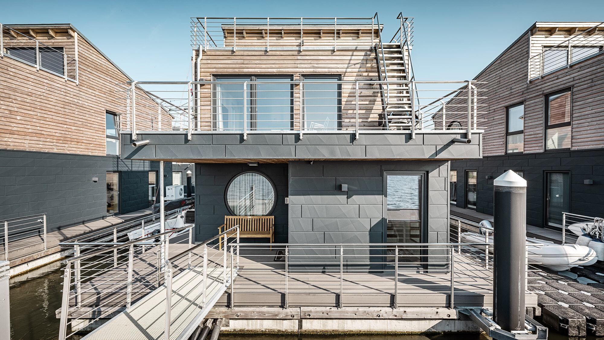 One of the houses up close from a normal perspective: the timber and aluminium façades are in view, the Schlei is reflected in the windows.