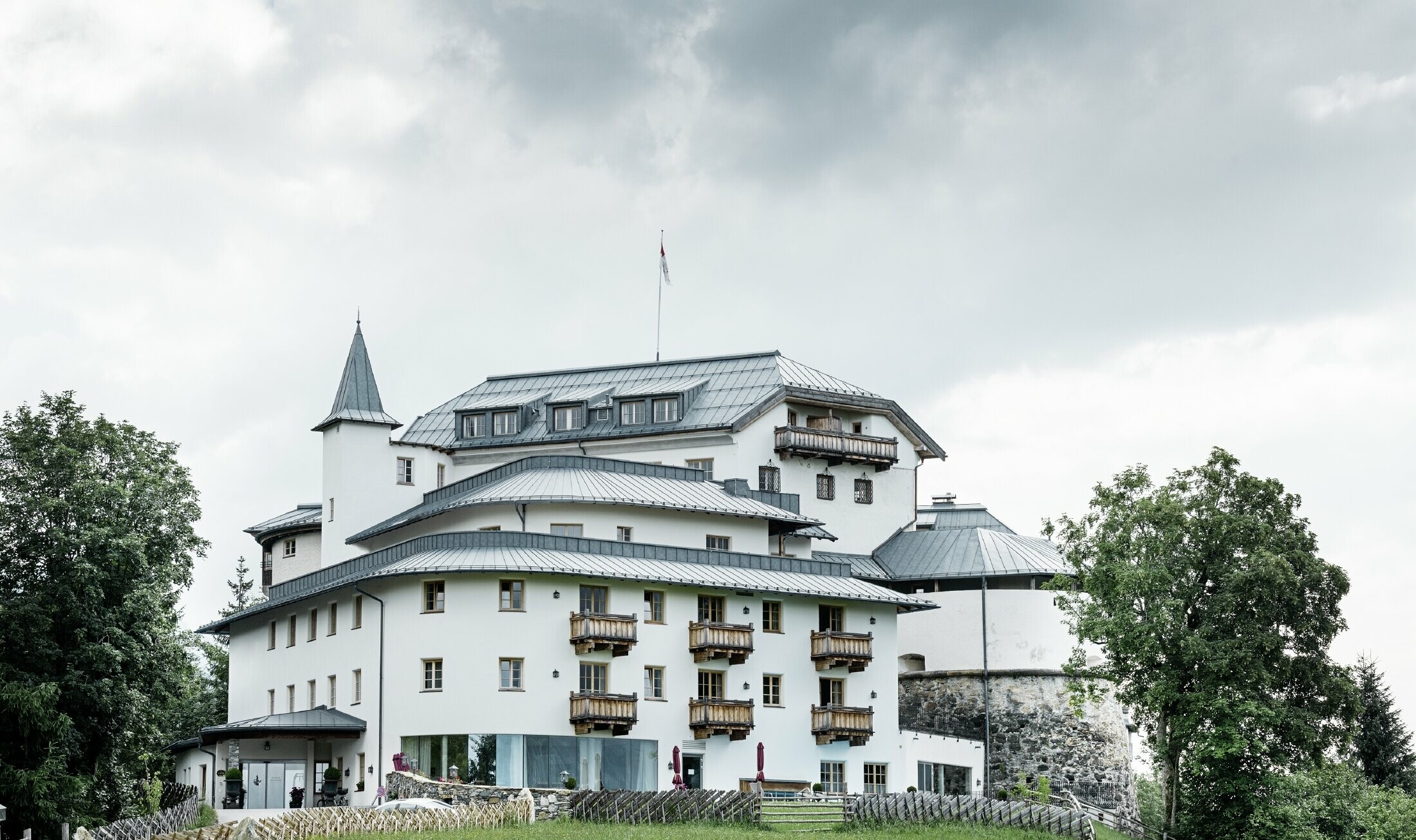 Mittersill Castle surrounded by trees and mountains with a recently renovated Prefalz roof in stone grey