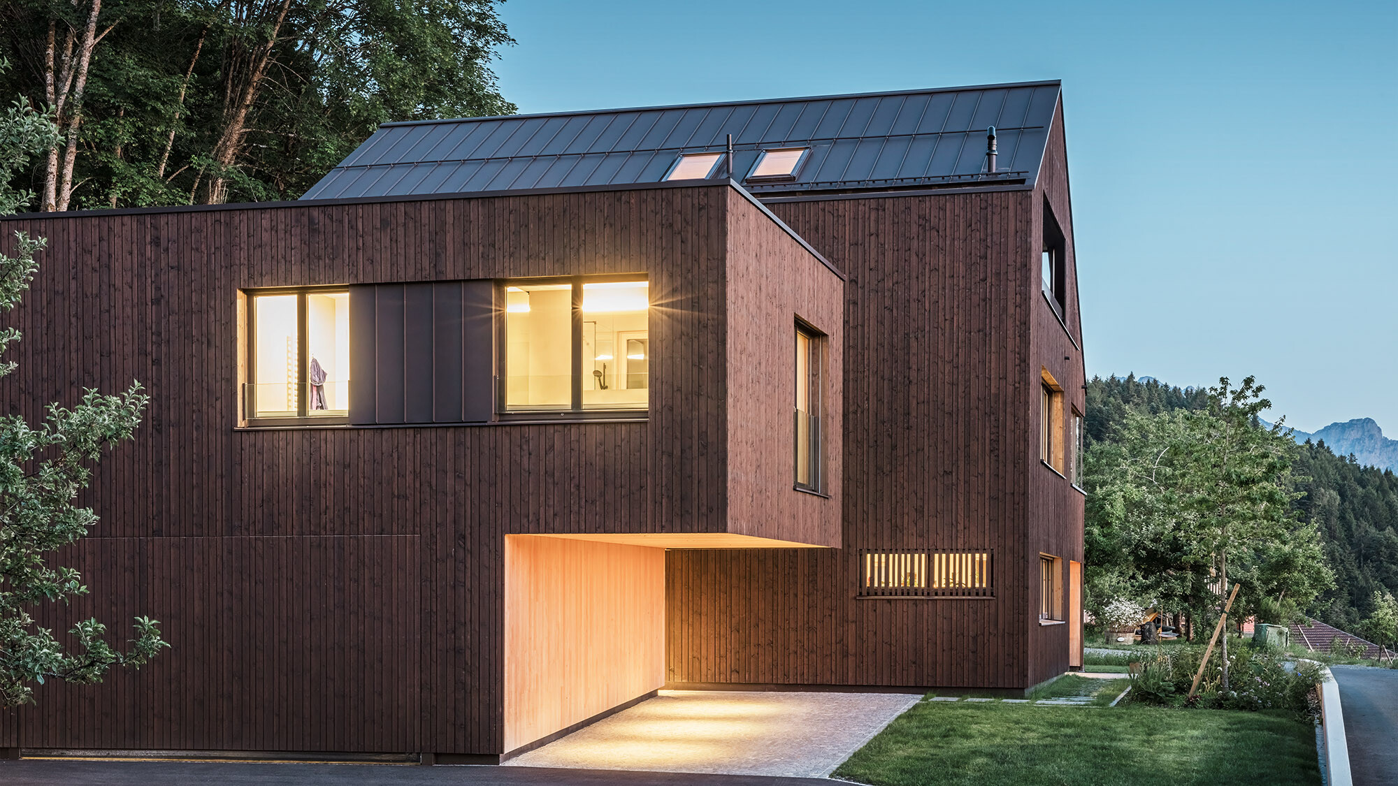 Evening shot of the multi-family home illuminated from the inside from a lateral perspective.