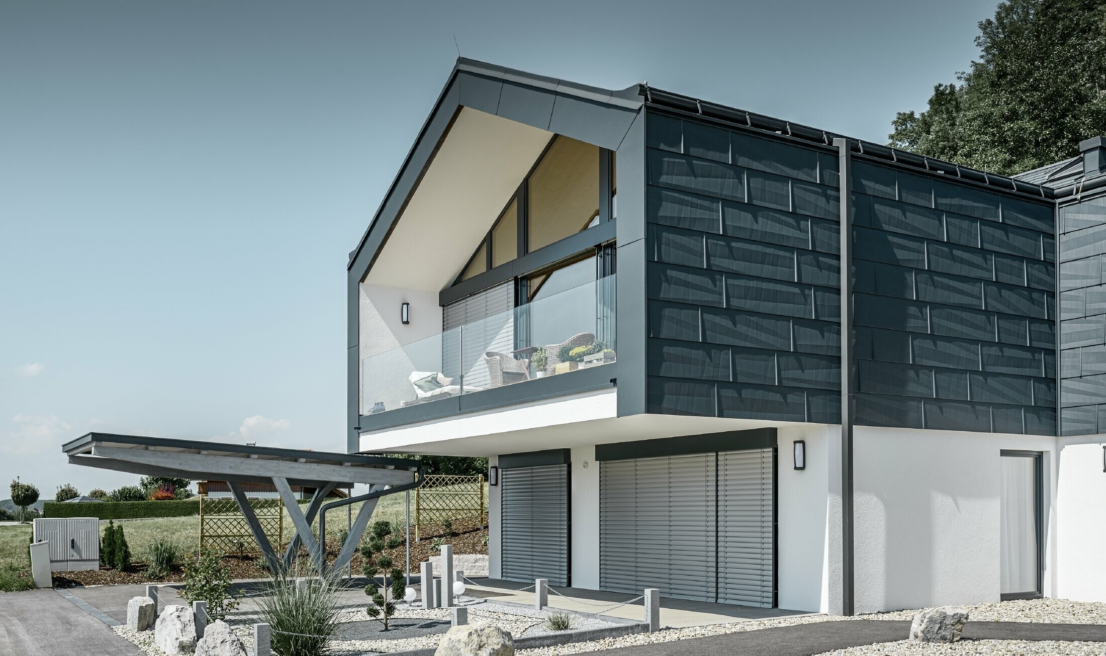 Modern apartment building with a large glass front, roof and façade were clad in the PREFA roof and façade panel FX.12 in anthracite