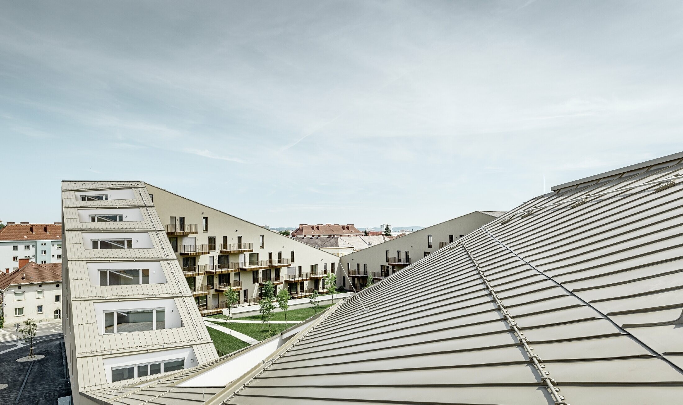 Extended residential complex with a flat roof surface and integrated terraces, generous windows and a Prefalz roof in the special colour of metallic bronze