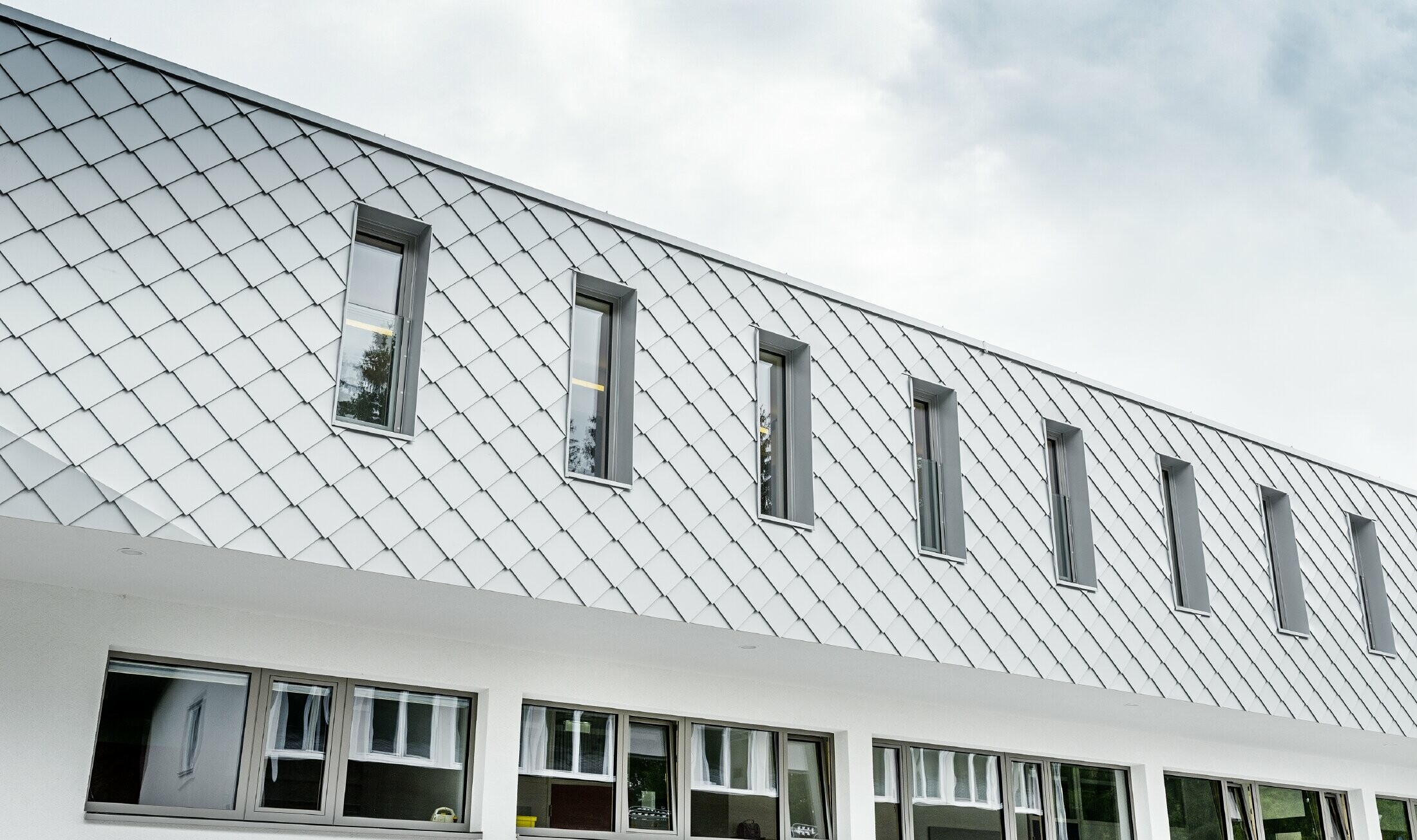 Newly built kindergarten in Kaprun with a modern aluminium façade with the PREFA rhomboid façade tile in PREFA white