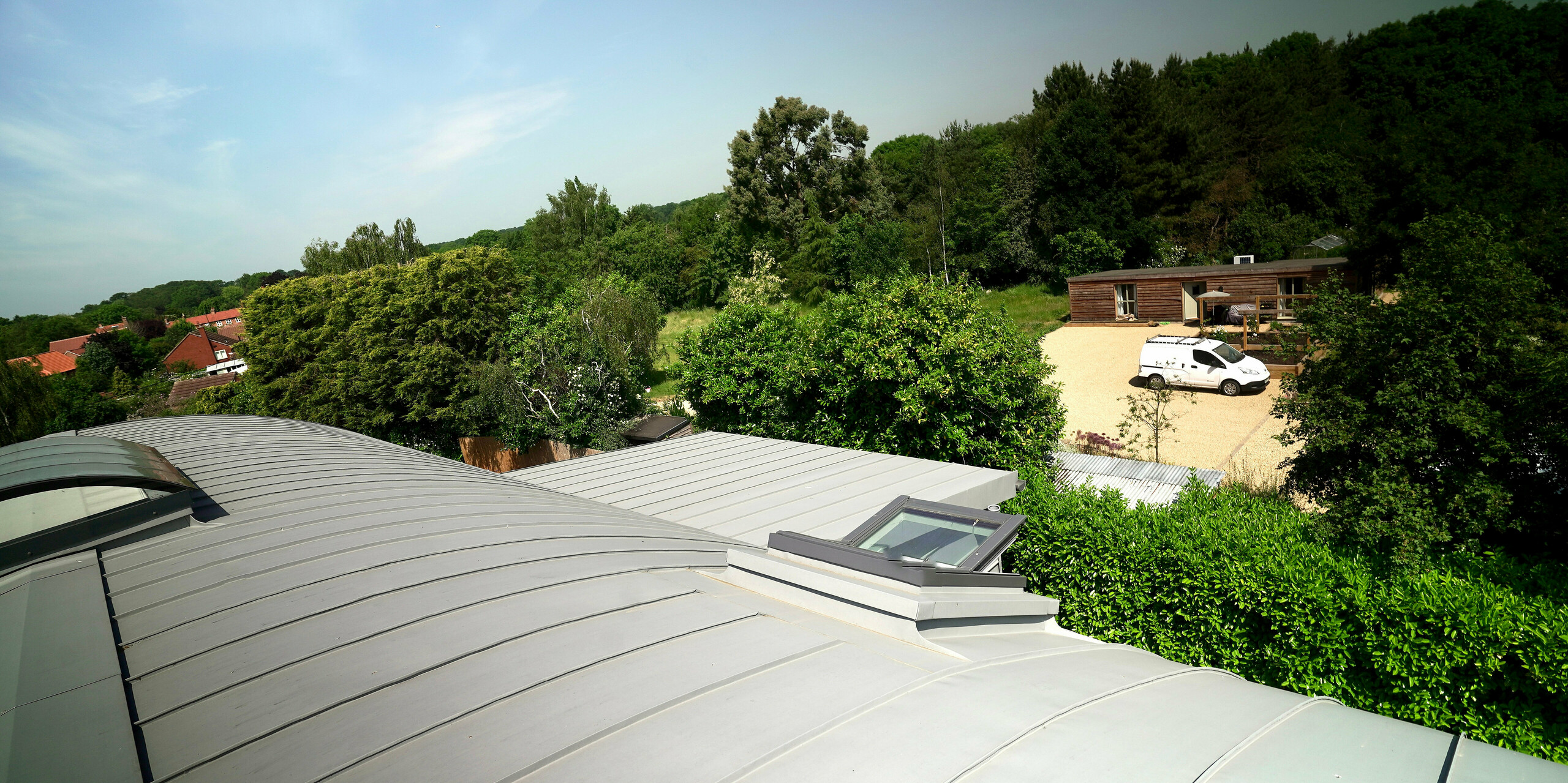 The roof of a Dutch barn was covered with PREFALZ in patina grey. The building is surrounded by several farmhouses.