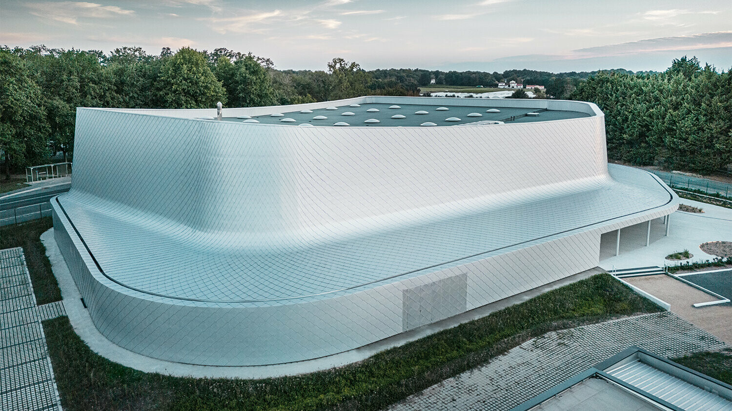 Lateral bird eye's view of the building with its immediate surroundings and a view of the roof's surface.