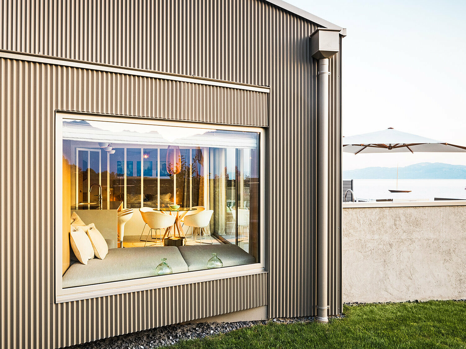 Side view of the building with a serrated aluminium façade, part of the illuminated interior is visible.